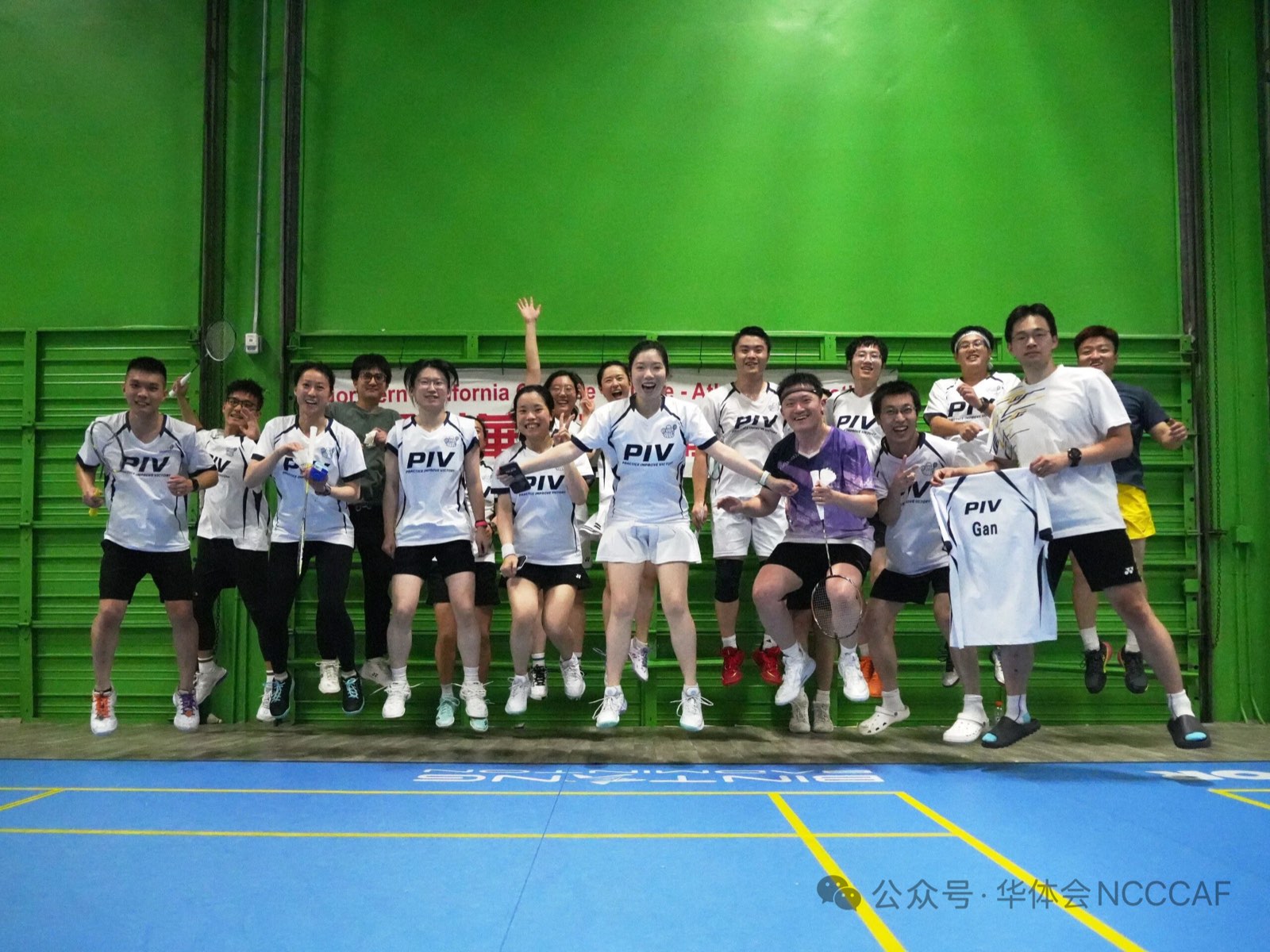 PIV Club players in matching white PIV jerseys jumping and cheering together on court at the NCCCAF badminton tournament